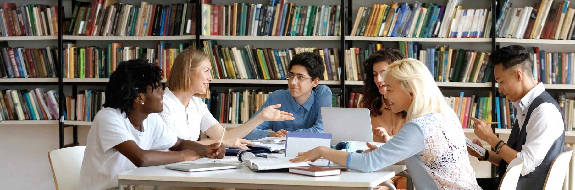 happy multiethnic group of people studying together in a library