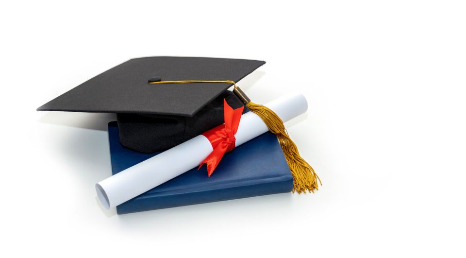 graduate's mortarboard cap resting on rolled up diploma