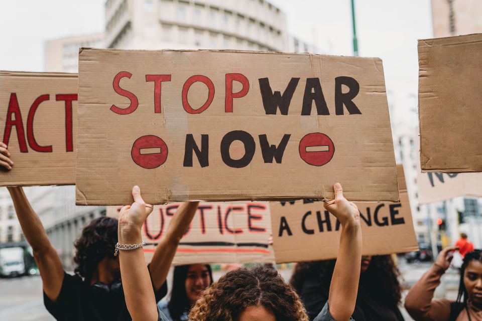 protesters holding signs with antiwar slogans such as stop war now