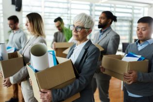 several persons walking through building carrying boxes of belongings