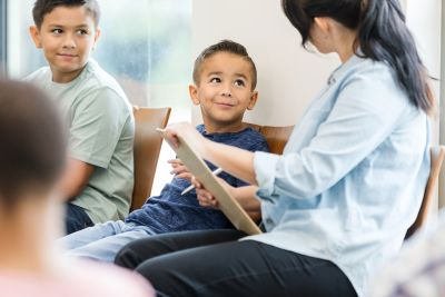 two children smiling and looking up at a teacher