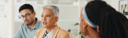 2 women and a man talking at a table