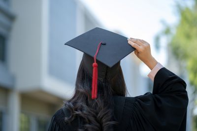 Student wearing graduation gown and holding cap