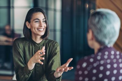 woman smiling and talking to other person in foreground