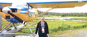 woman standing next to a 2-seater airplane
