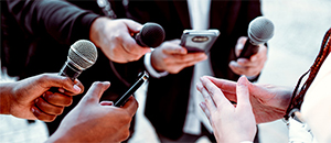 reporters point microphones at a person speaking