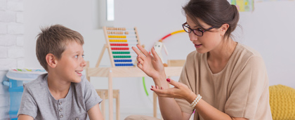 social worker talks with a young boy in a classroom