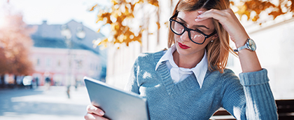 young woman on park bench reads on tablet