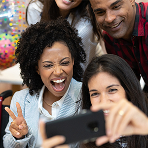 people in business casual clothes taking a group selfie