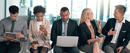 five adults reading screens or talking