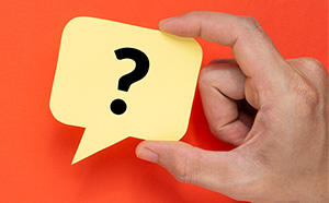 hand holds a sticky note with a question mark on it
