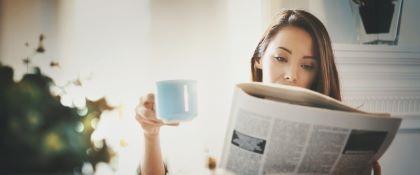 woman  reading a newspaper, drinking coffee