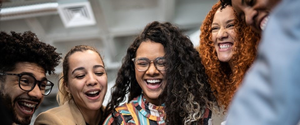People standing around smiling with their hands in the center