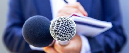 Hand holding microphones while holding a notebook