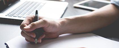 arm of person writing a letter at a desk