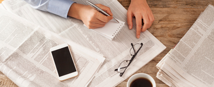 hands writing, with newspaper, coffee, eyeglasses