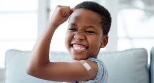 boy flexing his arm with a bandaid on it