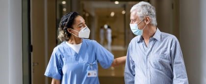 woman and man walking out of a hospital with masks on