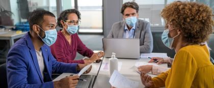 people in masks with documents around table