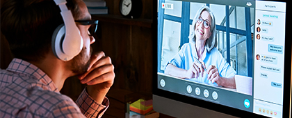 man with headphones watches a webinar on a computer