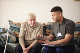 man showing elderly man content on a tablet while both sit on couch