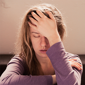 woman with head in hands, eyes closed