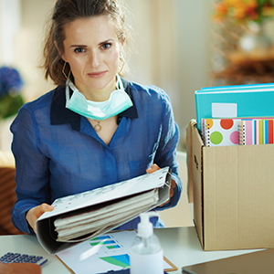 woman putting paperwork into box, a protective mask is down around her neck