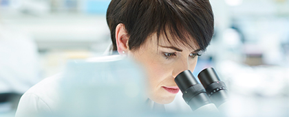 woman looking into microscope