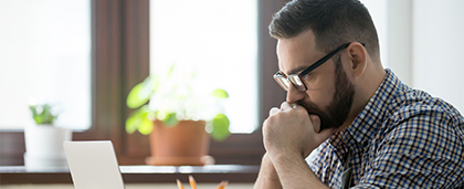 thoughtful man looking at laptop