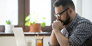 thoughtful man looks at laptop