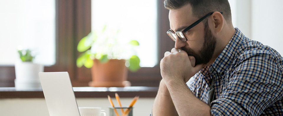 thoughtful man looking at laptop