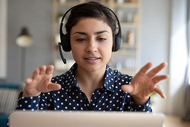 woman with headset talks into laptop computer