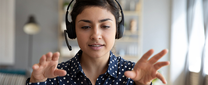 woman wearing headset talks into laptop