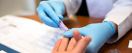 health care worker drawing blood from a patient's fingertip