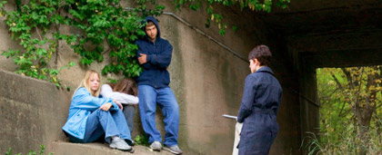 woman speaking with young people under a bridge