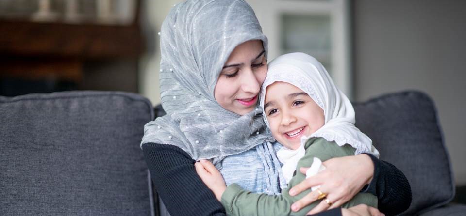 woman and daughter on couch in hijabs