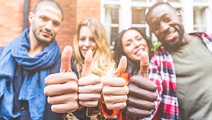 four smiling adults with thumbs up