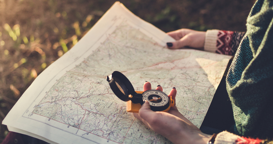 woman looks at a map with compass in her hand