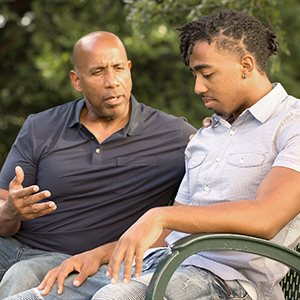 father and son talking on park bench