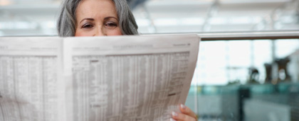 woman reads newspaper at an airport