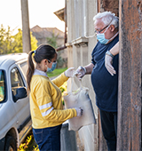 young adult delivering supplies to older man with gloves, protective face masks
