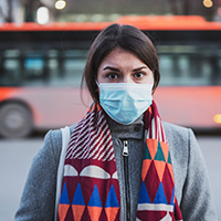 woman stands outside wearing a face mask