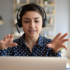 woman wearing a headset looks at laptop, gestures with both hands