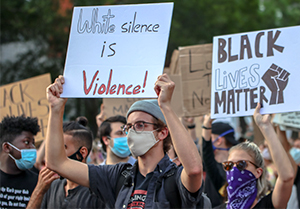 protesters holding signs: white silence is violence and black lives matter